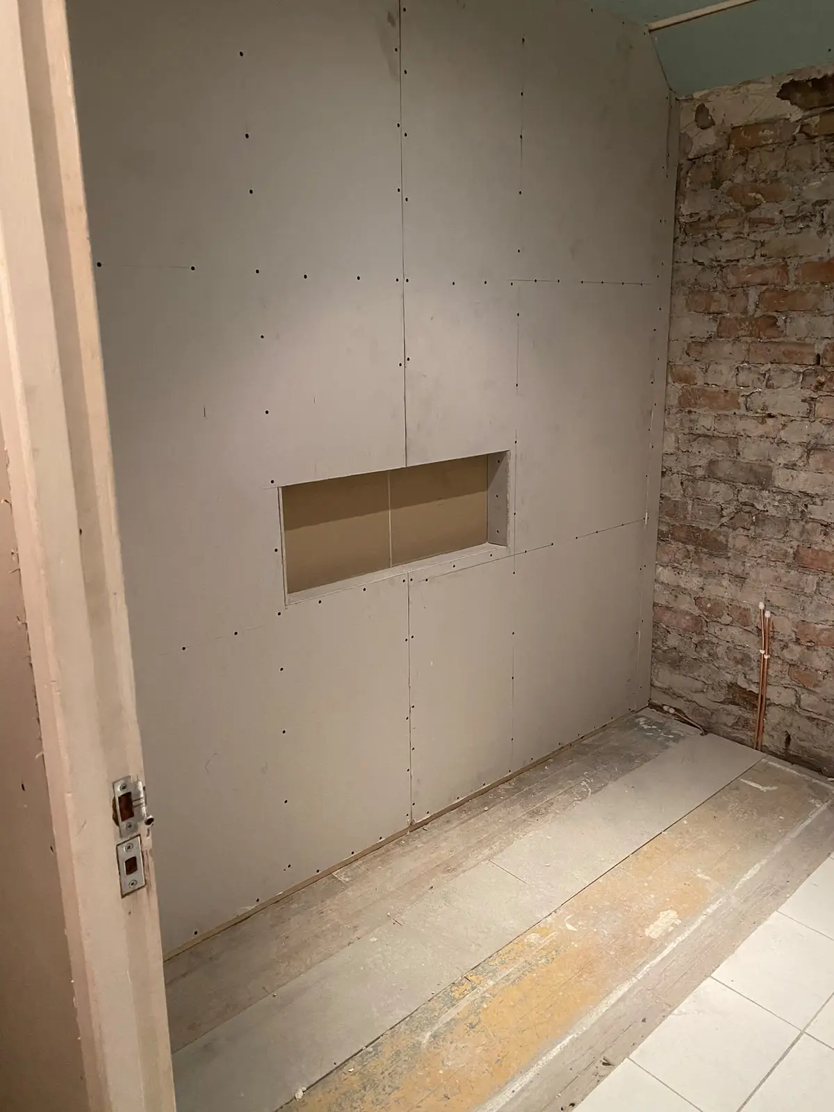 Walls boarded, with an alcove formed in the shower wall