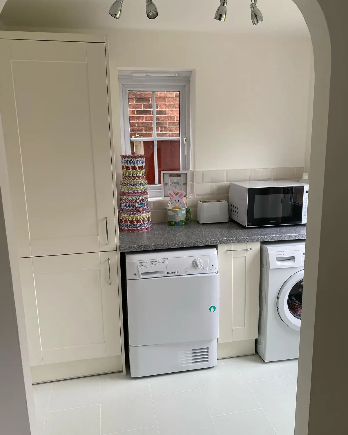 Cream shaker tall unit beside the washing machine and dryer