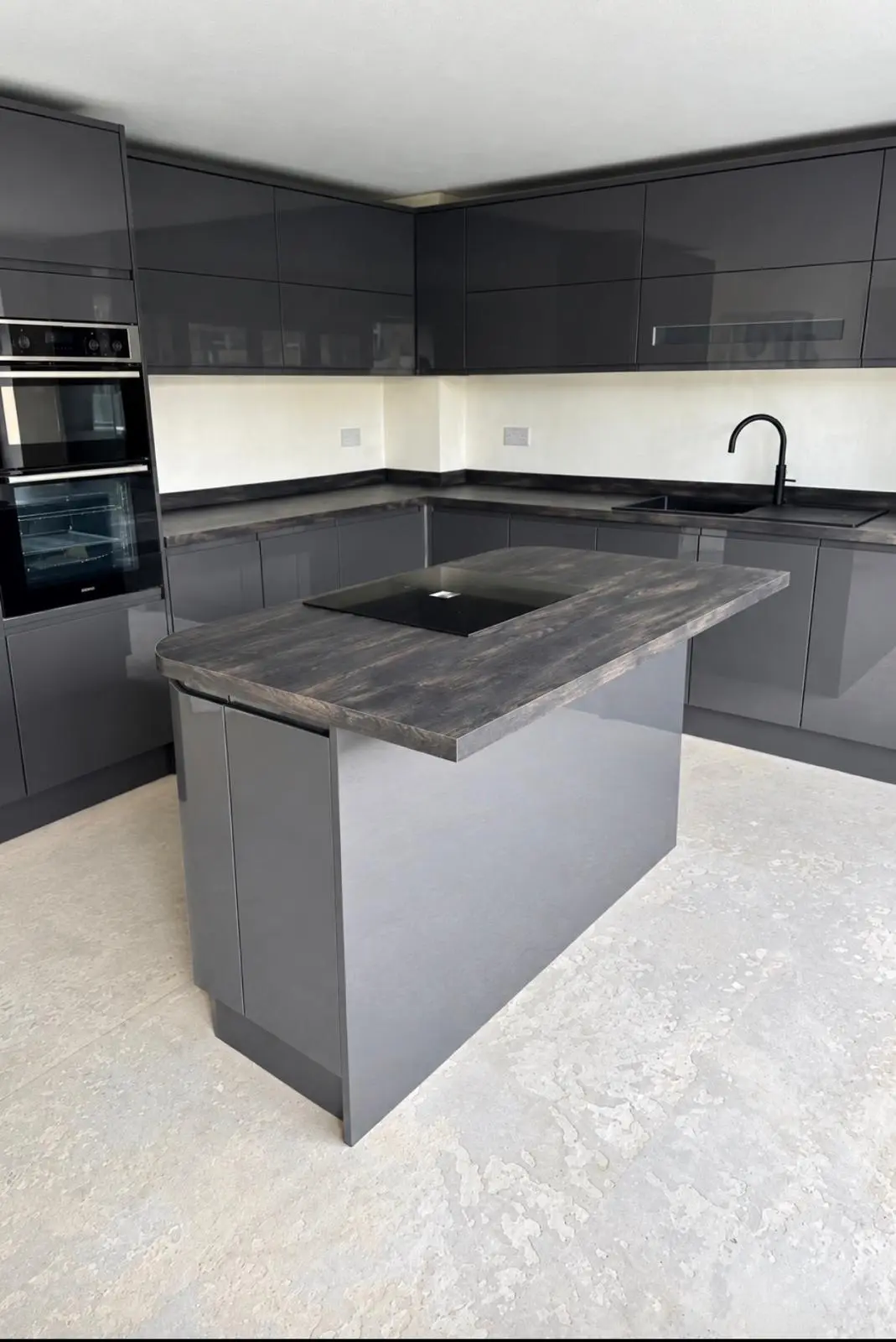 Graphite gloss island with induction hob in front of the sink run