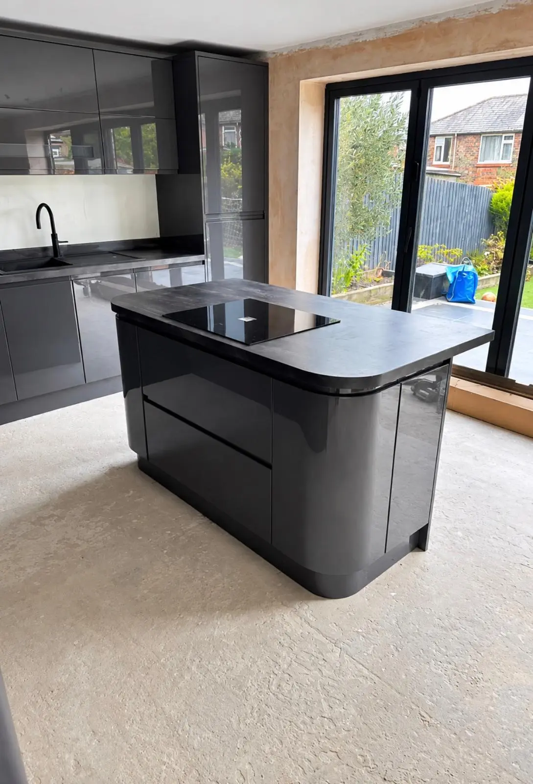 Curved-end island with induction hob, in front of glazed doors to the garden