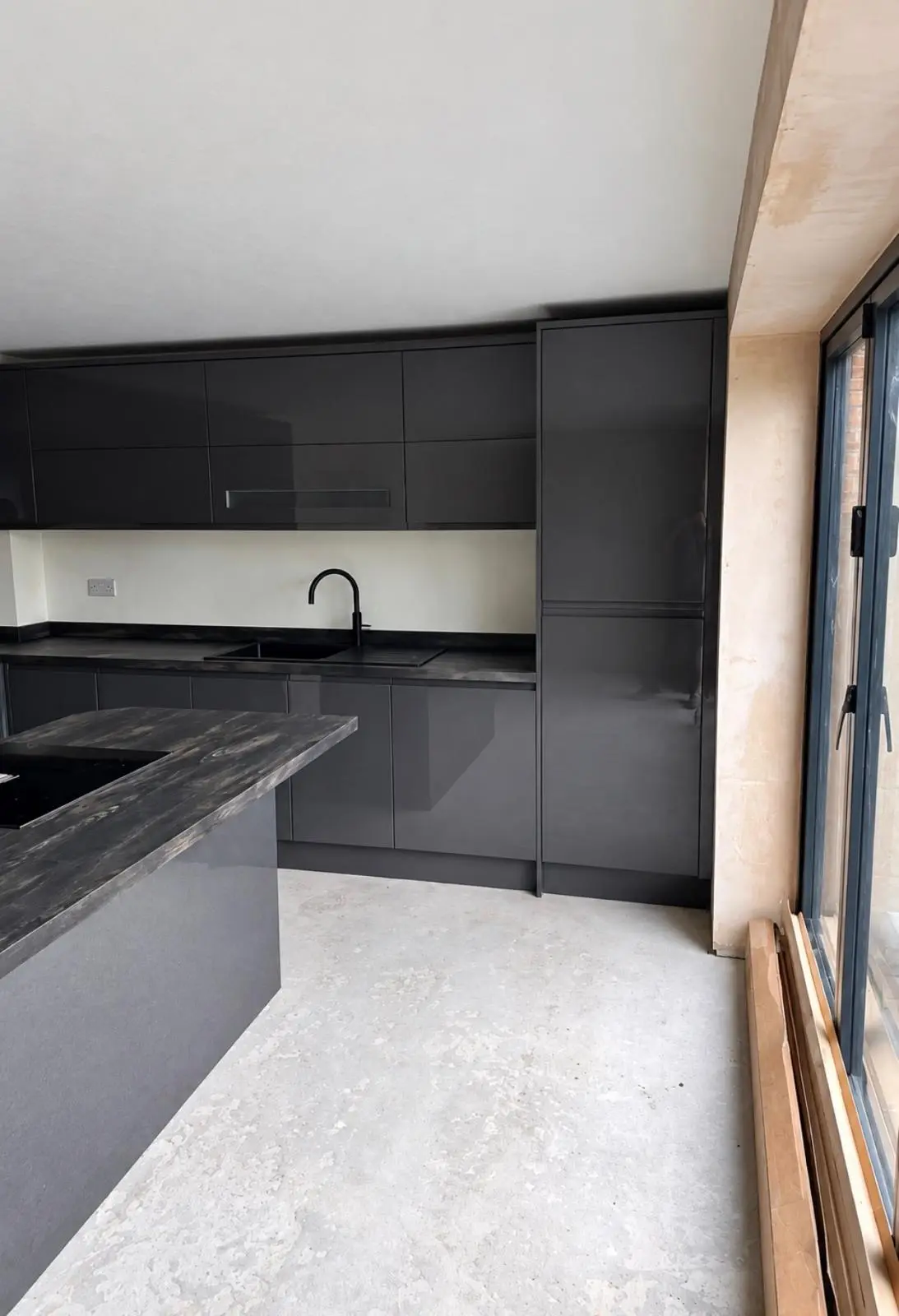 Graphite gloss sink run and wall units beside the garden doors