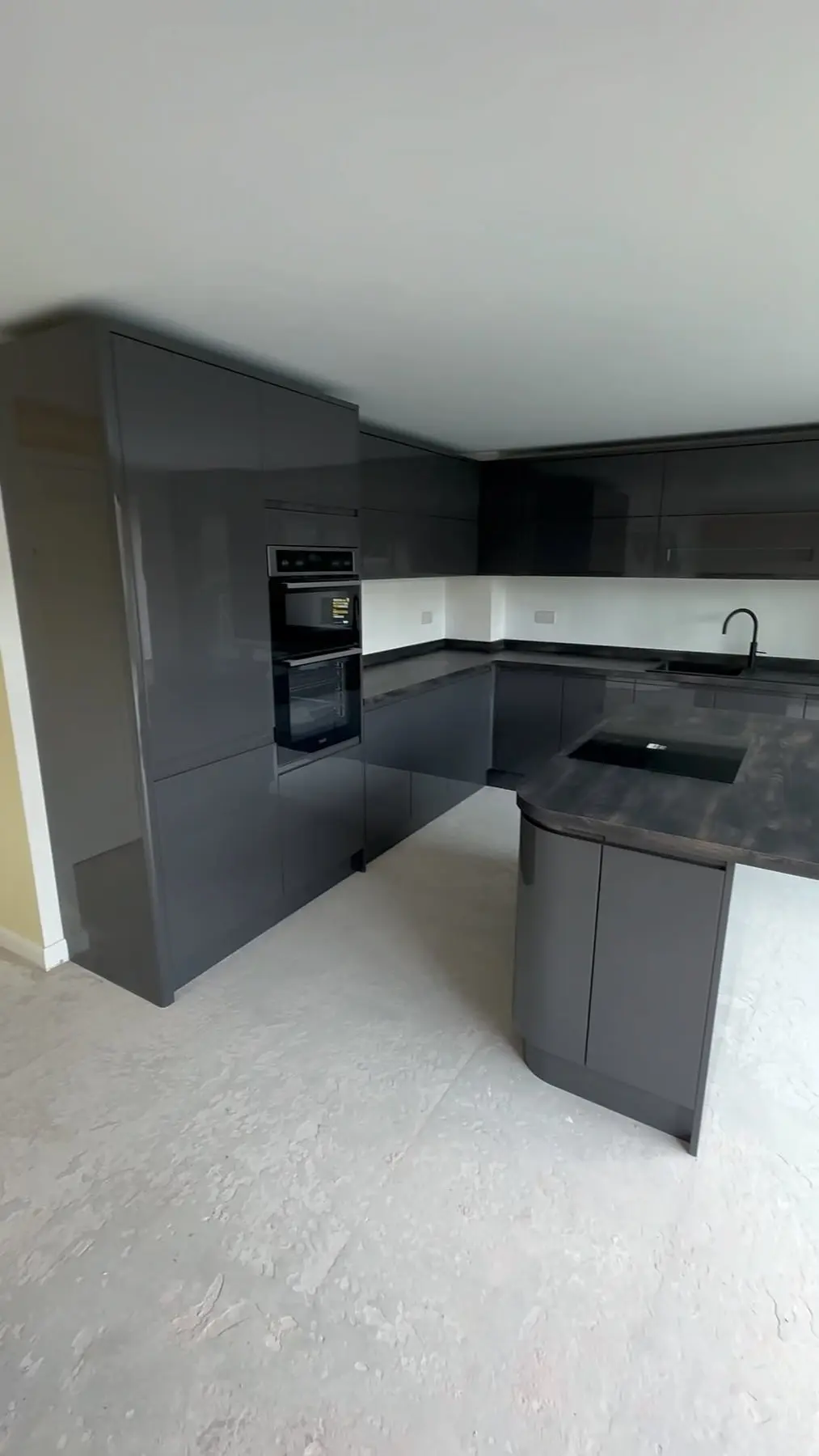 Graphite gloss handleless kitchen with a curved-end island and dark worktops