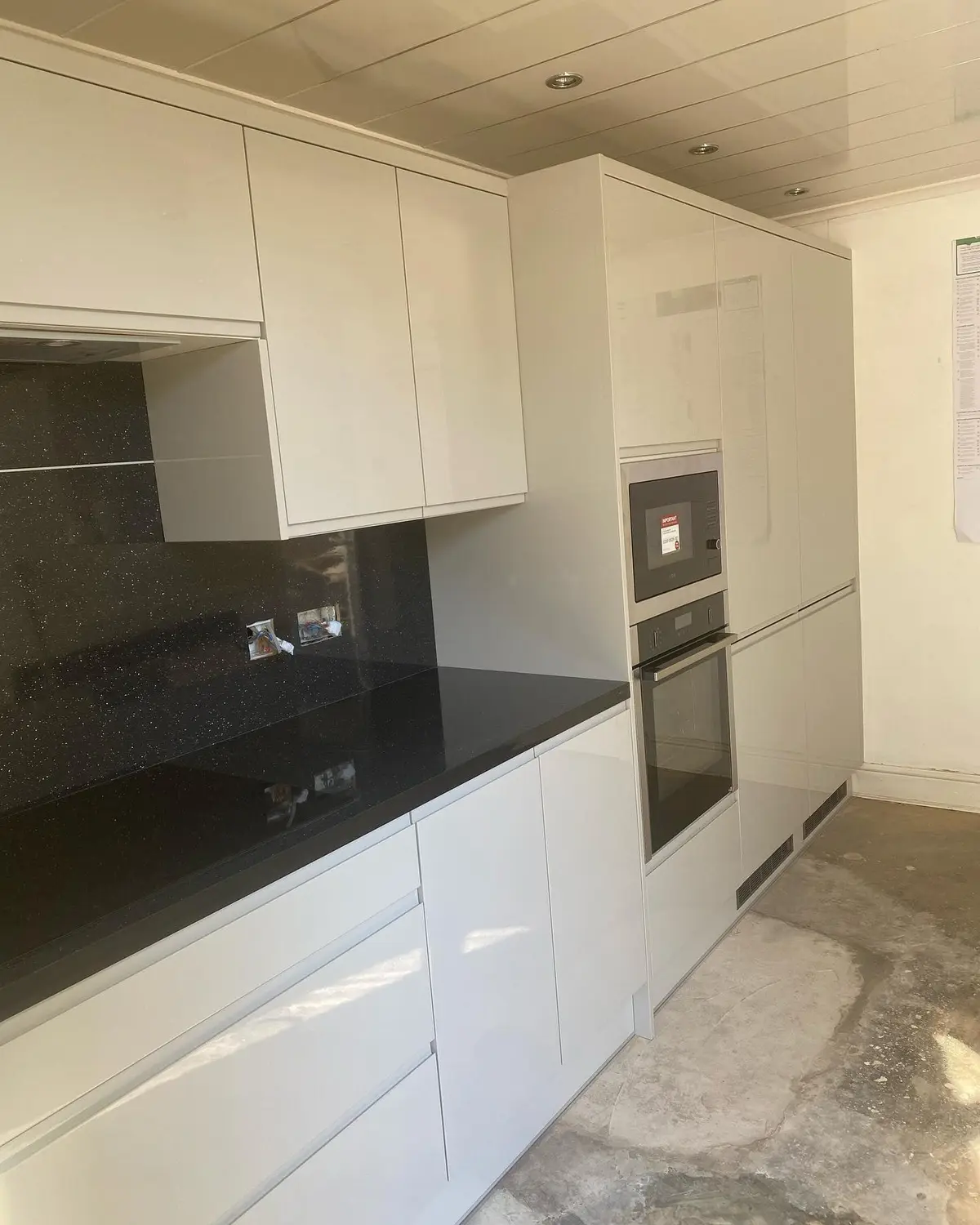 White gloss wall and base units with black worktop and built-in oven