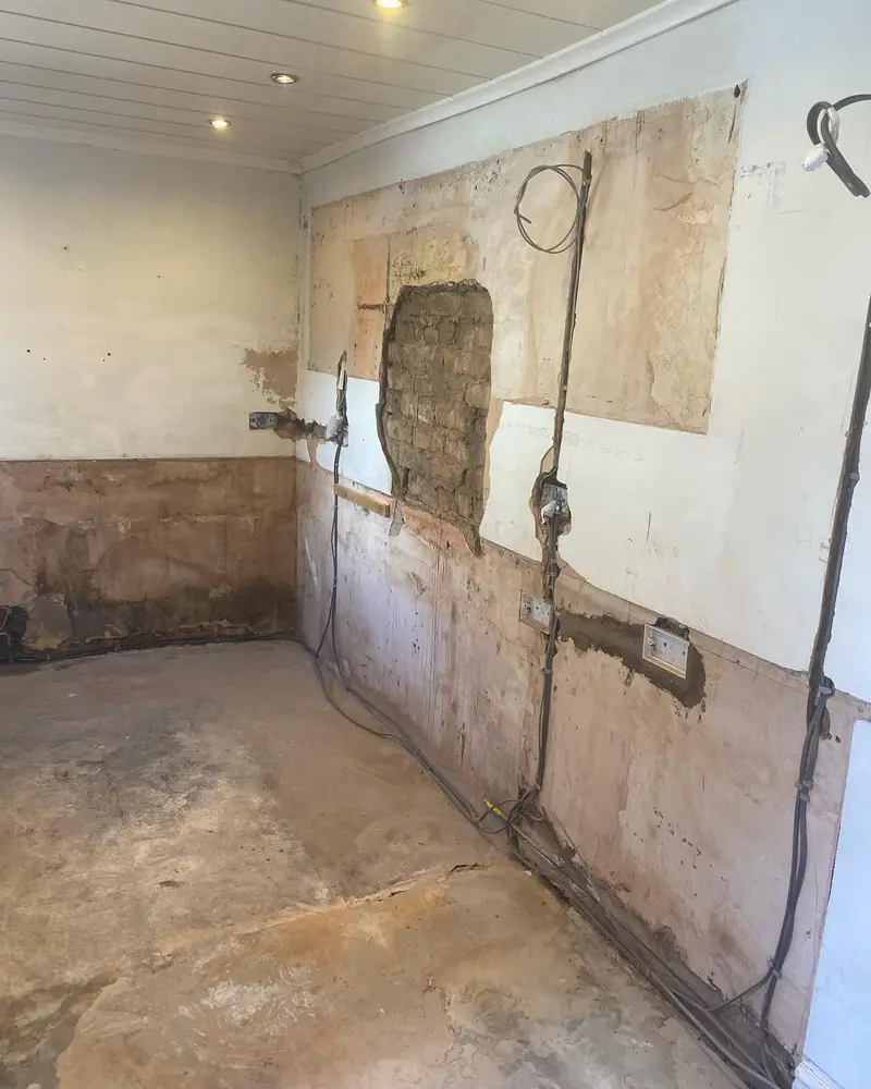 Stripped kitchen wall with first-fix cables and a patched opening