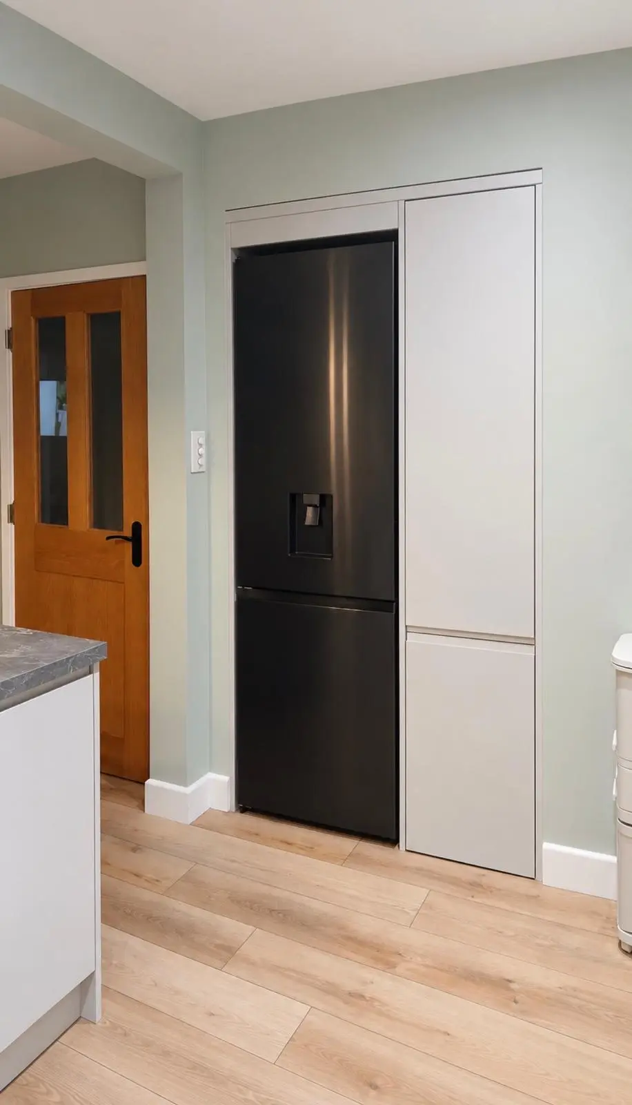 Fridge freezer housed beside a light grey J-pull tall unit, on oak LVT flooring