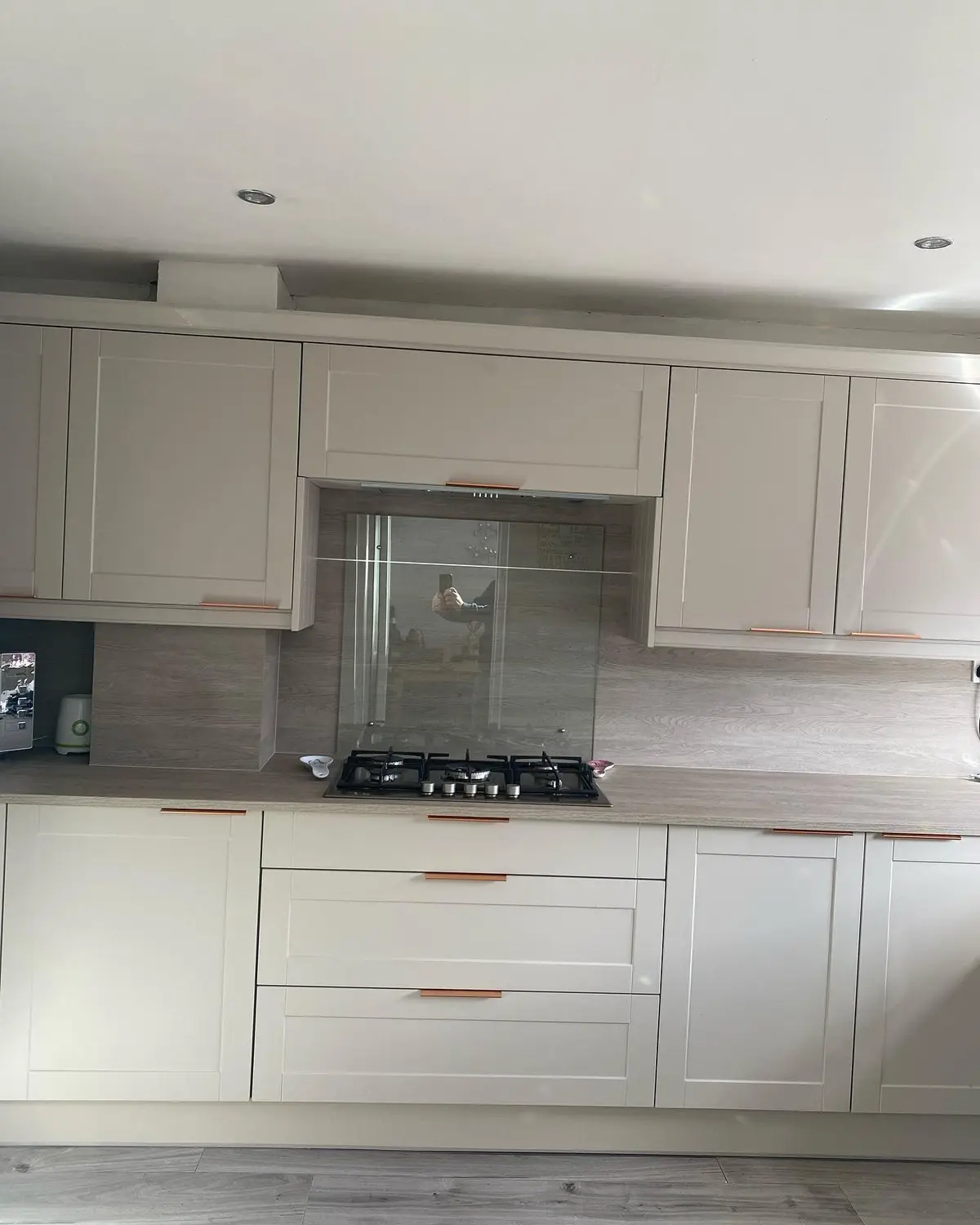 Light shaker run with a gas hob and glass splashback panel