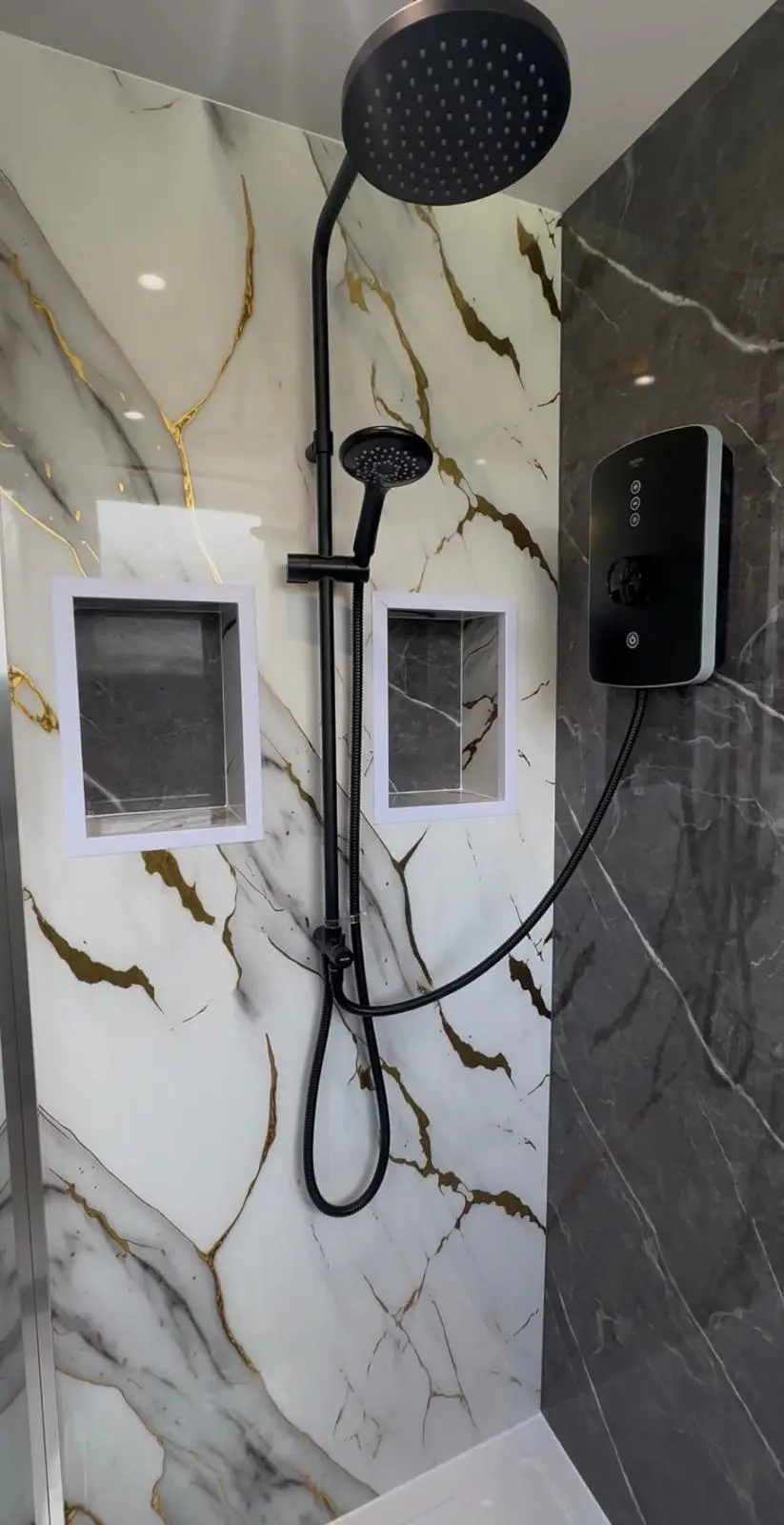 Black rain shower, electric shower unit and two alcoves on gold-veined marble-effect panels
