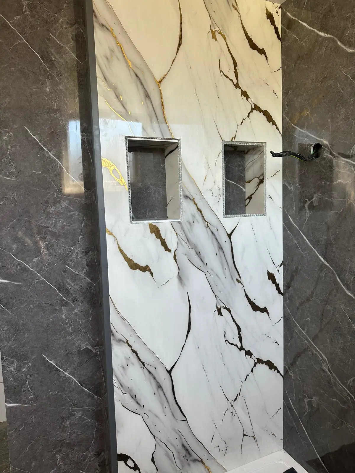 Two recessed alcoves in the marble-effect shower wall