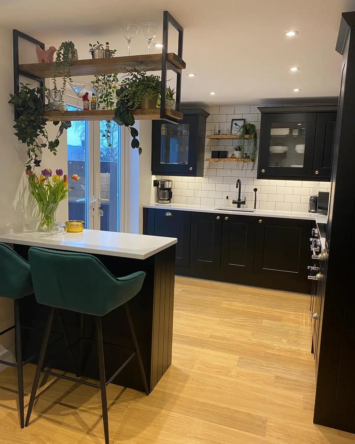 Matt black shaker kitchen with a peninsula and green velvet bar stools