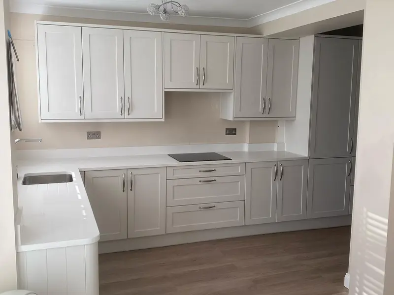 Light shaker kitchen with white quartz worktops and upstands on a wood-effect floor