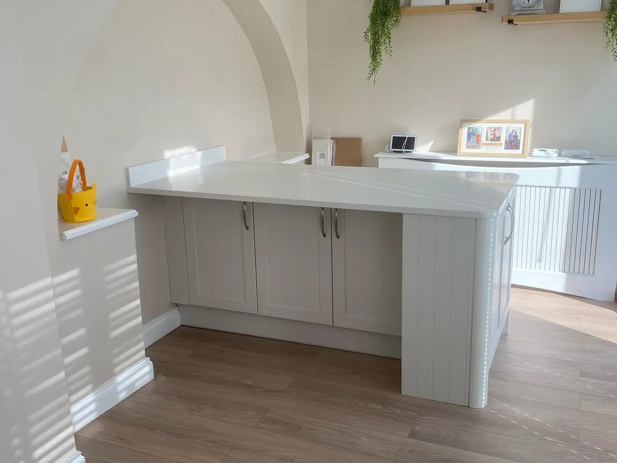Shaker peninsula and breakfast bar with white quartz worktop and an arched alcove behind