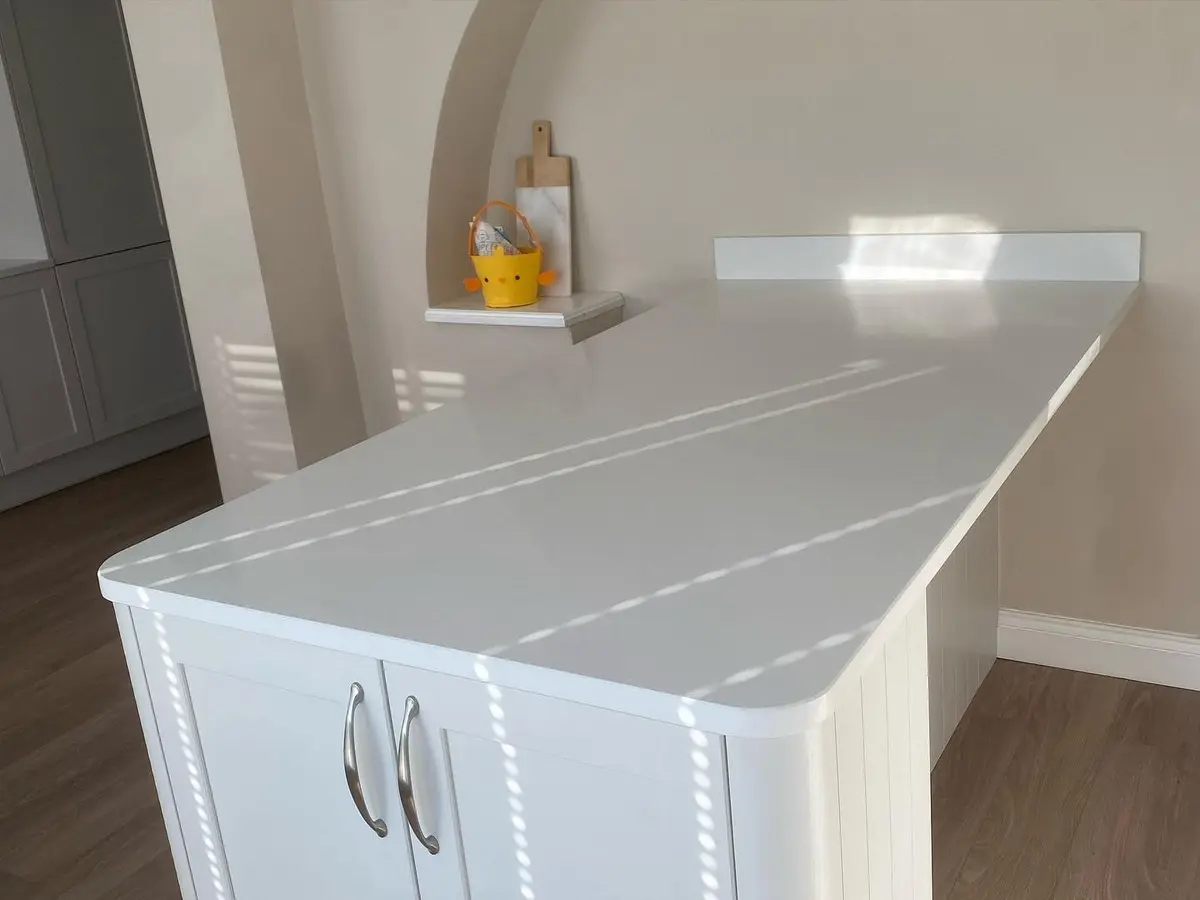 Curved-end peninsula with white quartz worktop over light shaker units