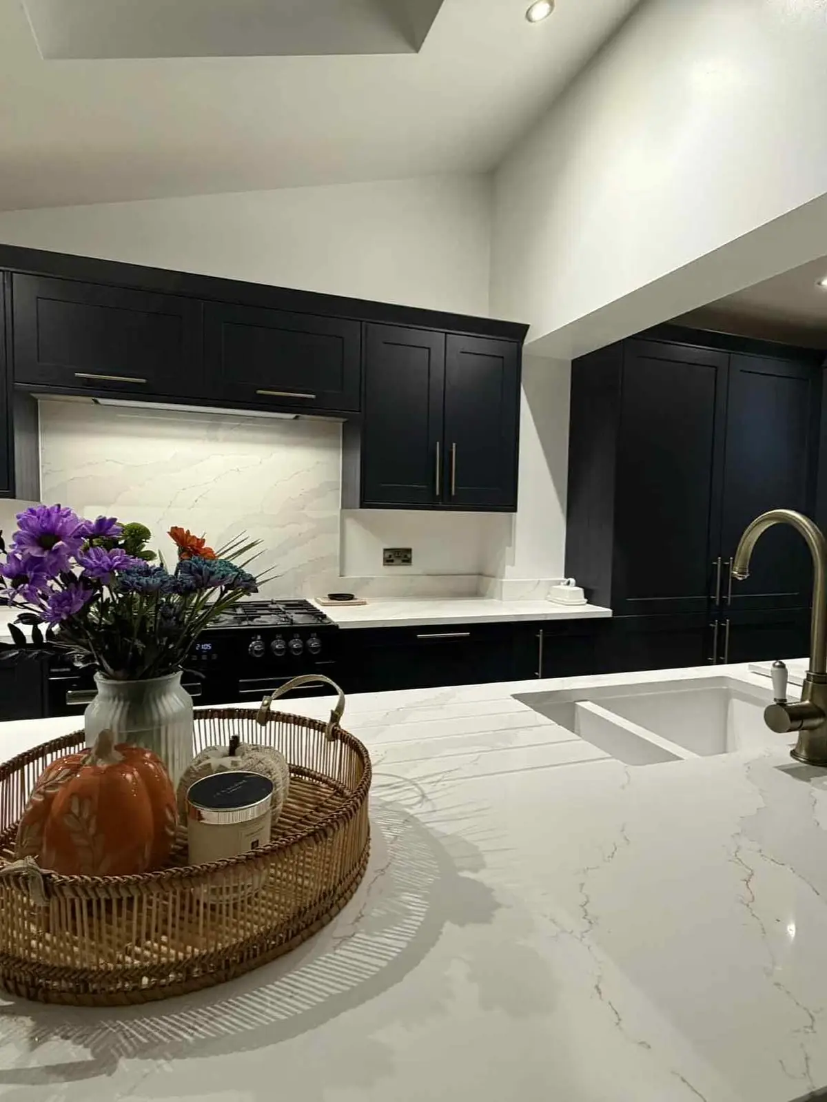 Navy shaker island and range cooker run, with flowers on the white quartz worktop