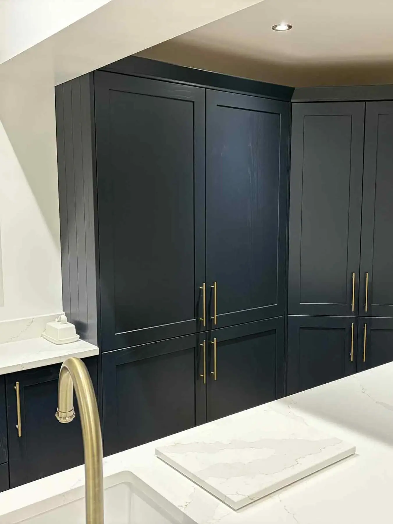 Close-up of navy shaker tall units with brass bar handles