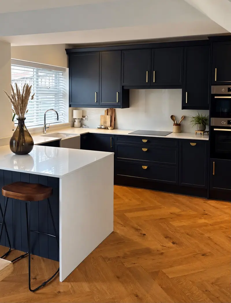 Navy shaker kitchen with a white quartz waterfall peninsula and bar stools on a herringbone wood floor