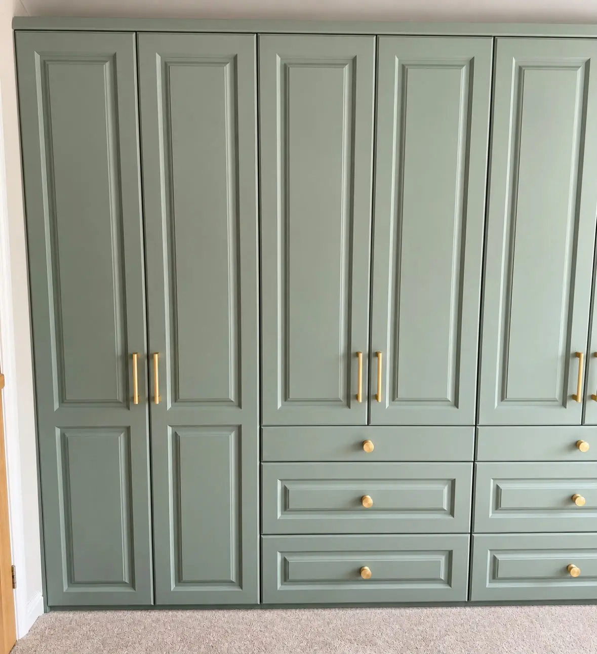 Sage green fitted wardrobes with brass handles