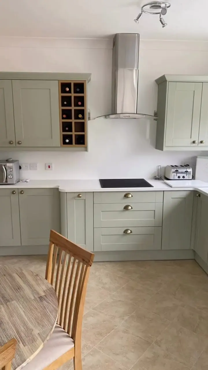 Sage shaker kitchen with white quartz worktops, a wine rack unit and a stainless chimney extractor