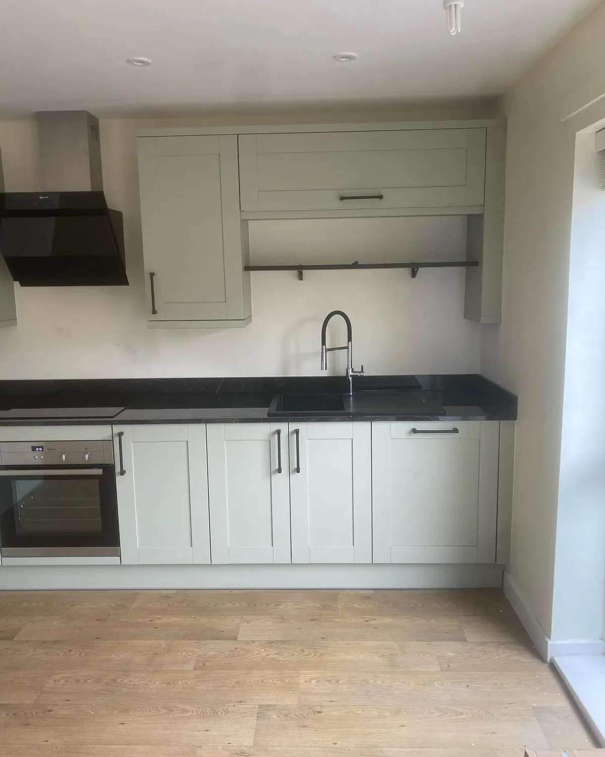 Sage green shaker wall and base units with black extractor