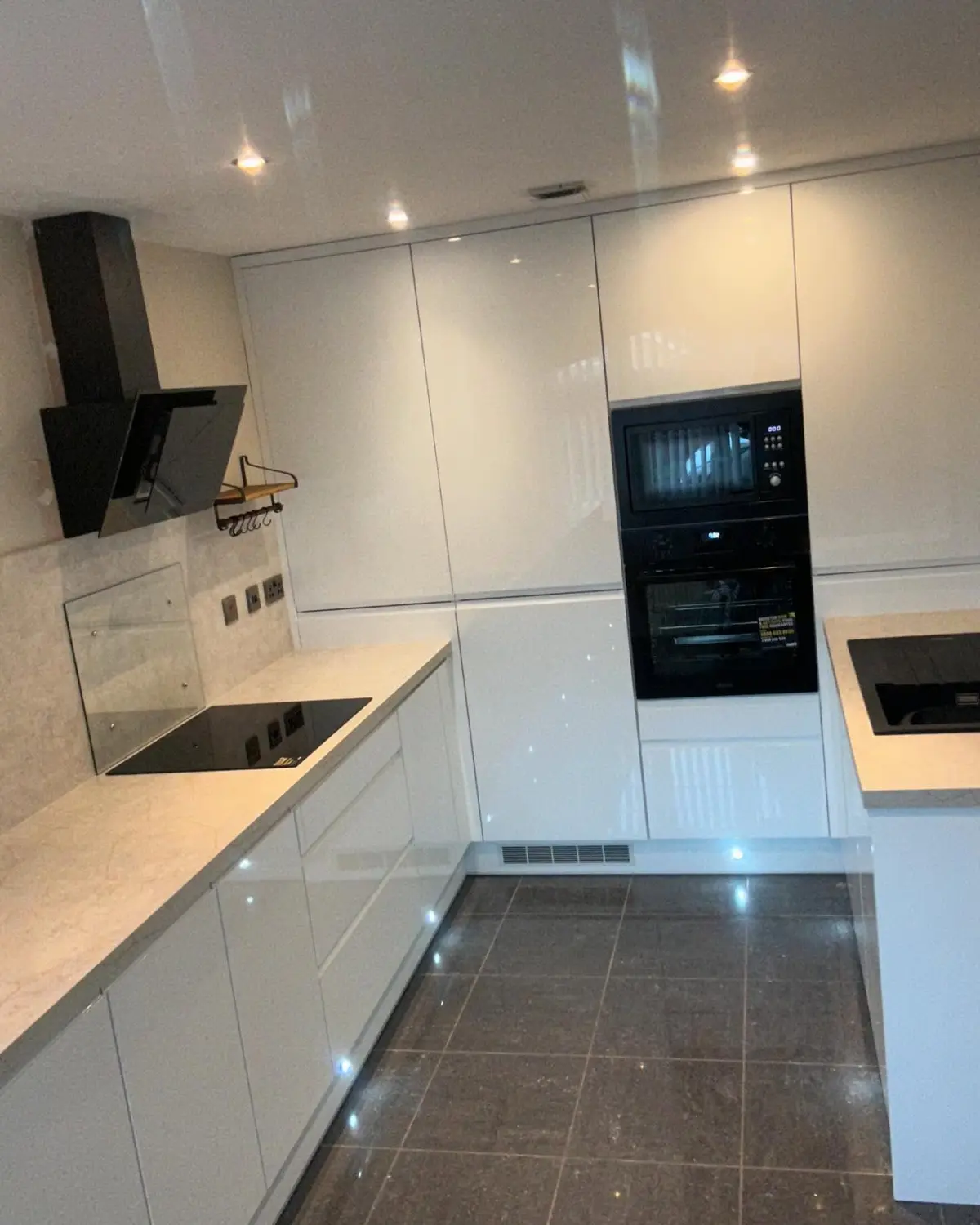 White gloss kitchen with black ovens and plinth lighting