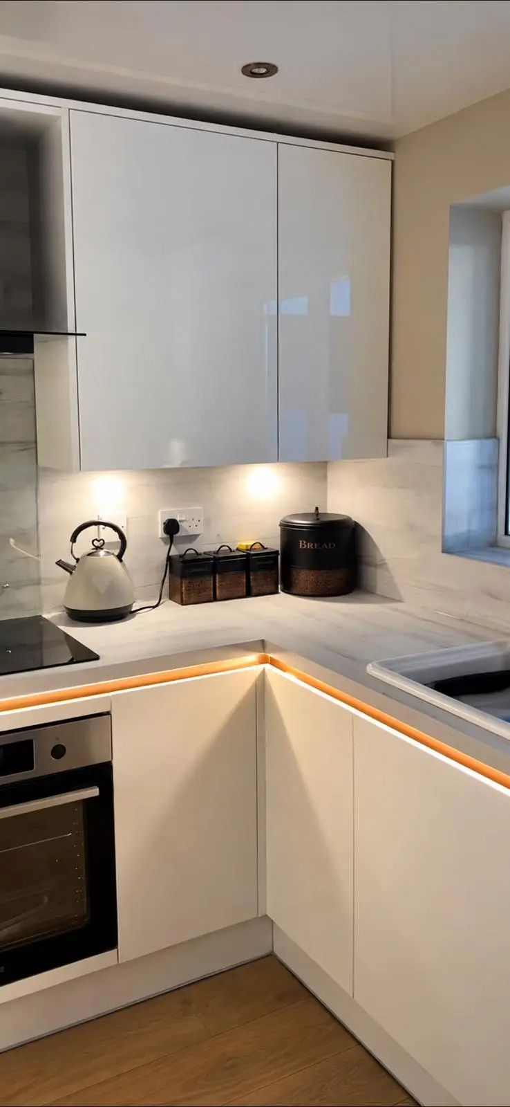 Corner run with built-in oven, white gloss wall units and warm white strip lighting