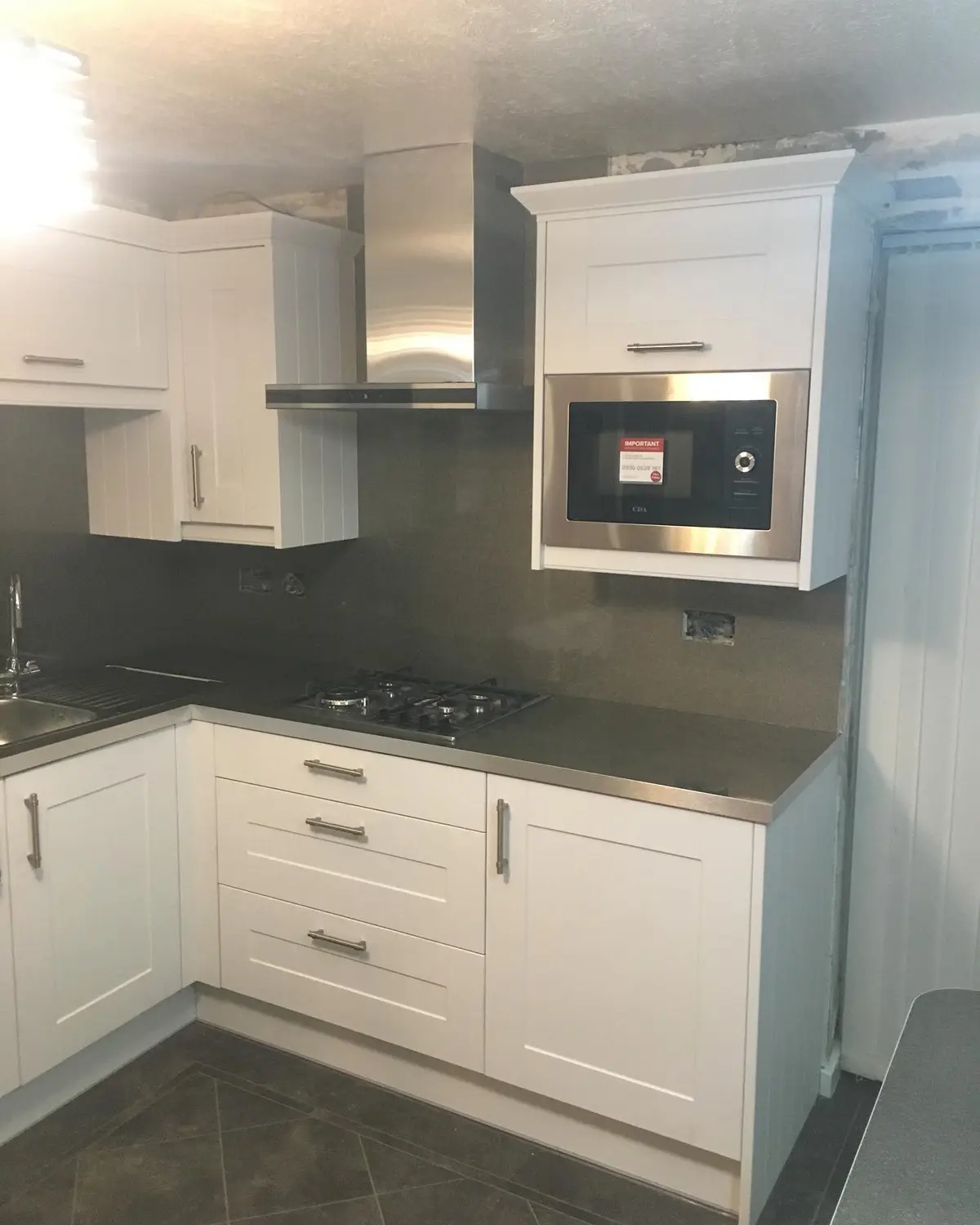 White shaker corner run with dark worktop, hob and built-in microwave