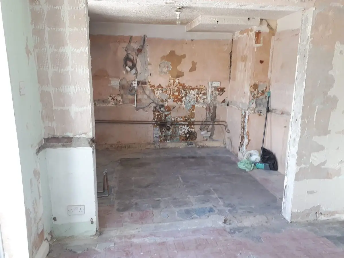 Kitchen stripped back to bare brick walls and floor, with old services exposed