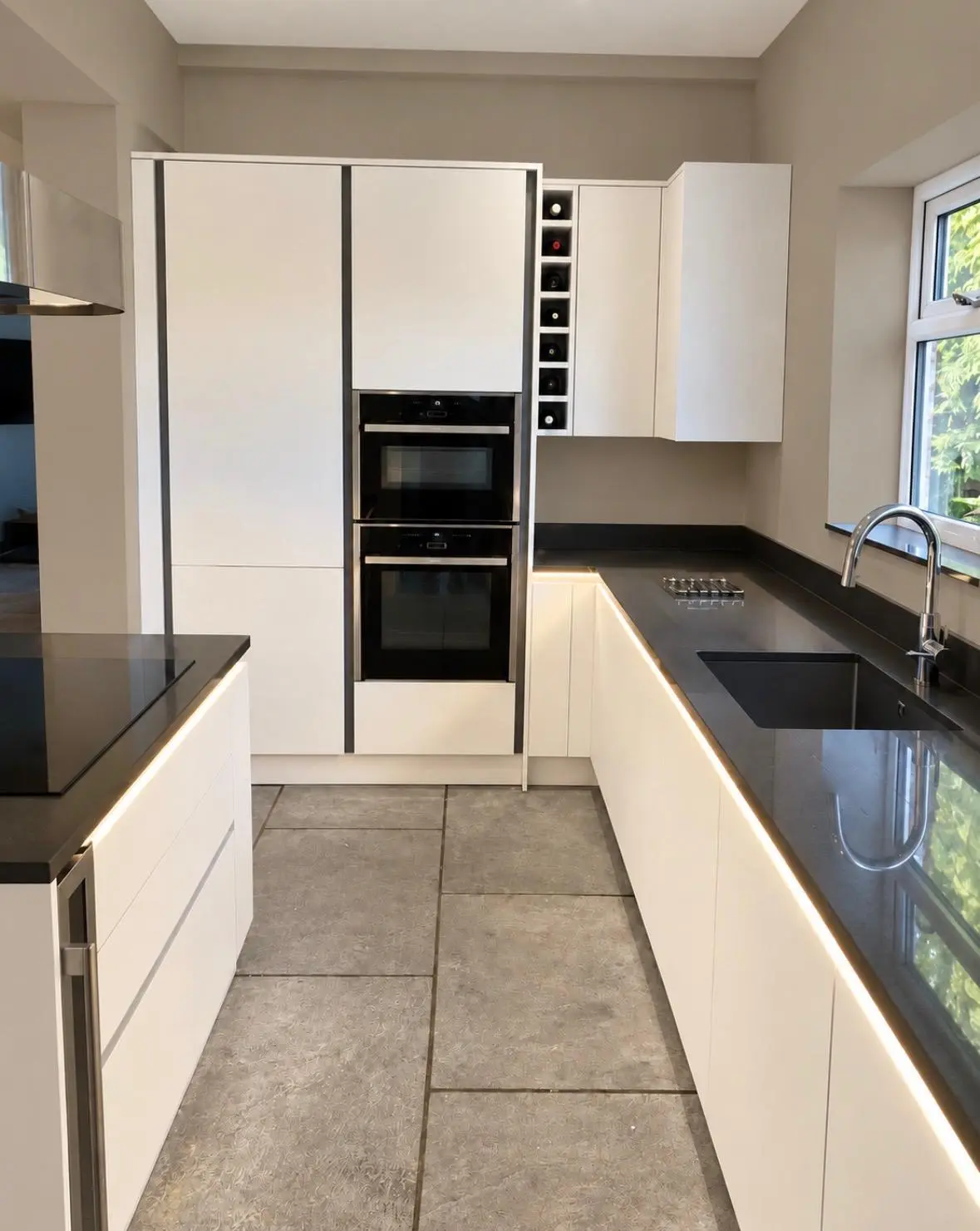 LED strip lighting running along white handleless base units under a black worktop