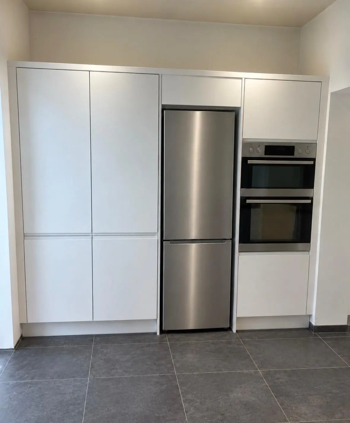 White handleless tall housings with a built-in double oven and a fridge freezer