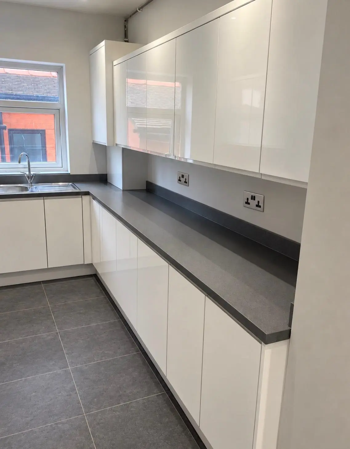 White gloss handleless run with grey sparkle worktop under the window