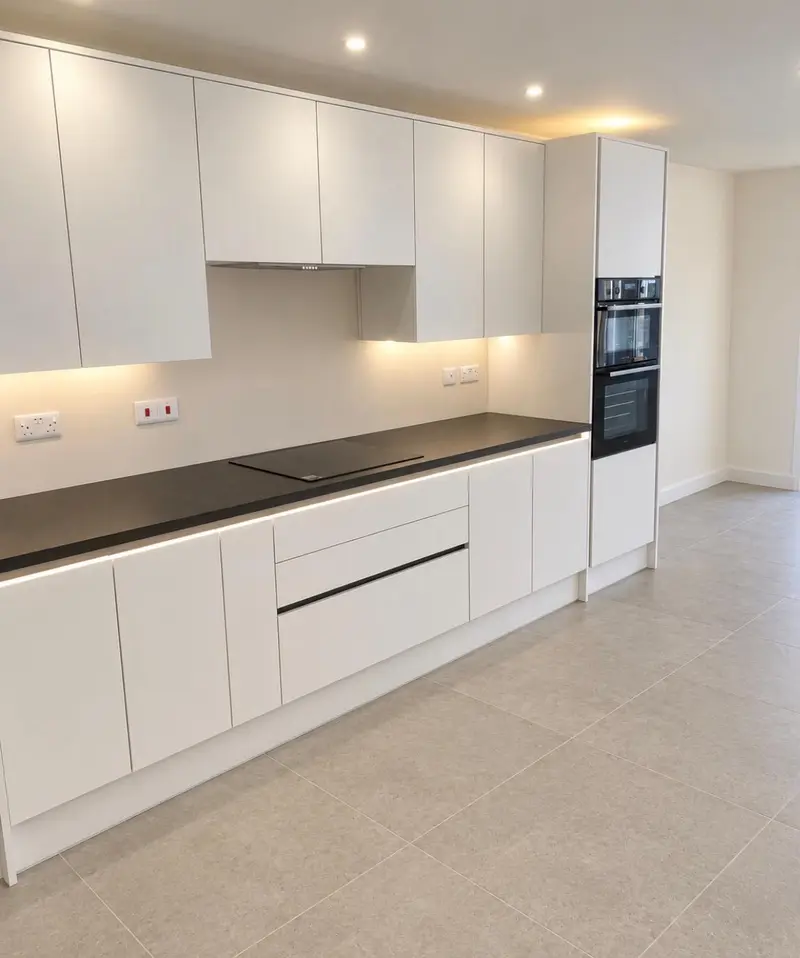White handleless run with black worktop and strip lighting along the black Milano rails