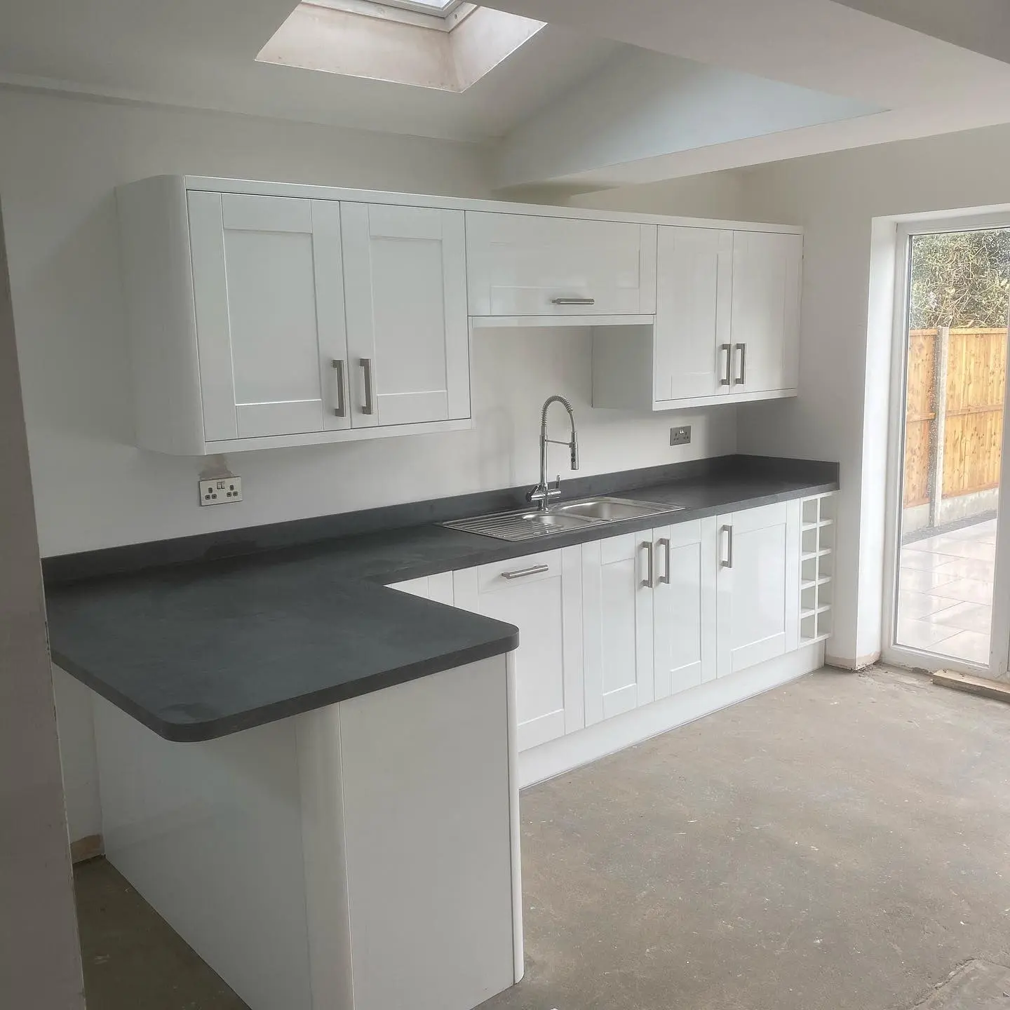 White shaker kitchen with grey laminate worktops beneath a roof light