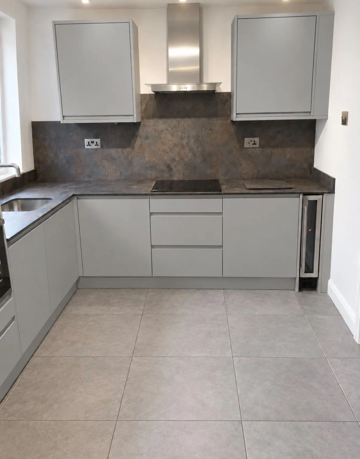 U-shaped grey J-pull kitchen with a stainless chimney extractor